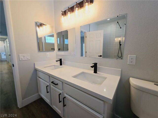 bathroom with vanity, wood-type flooring, tiled shower, and toilet