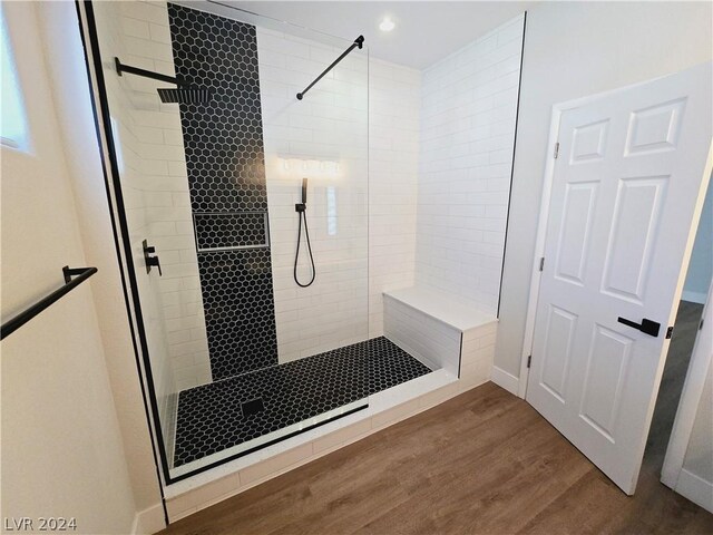 bathroom with a tile shower and hardwood / wood-style flooring