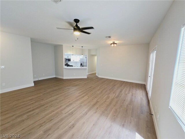 unfurnished living room with light hardwood / wood-style flooring and ceiling fan