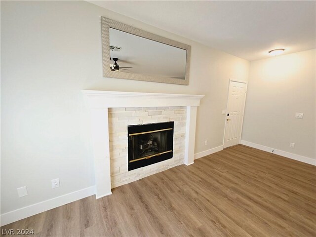 unfurnished living room featuring ceiling fan, hardwood / wood-style floors, and a fireplace