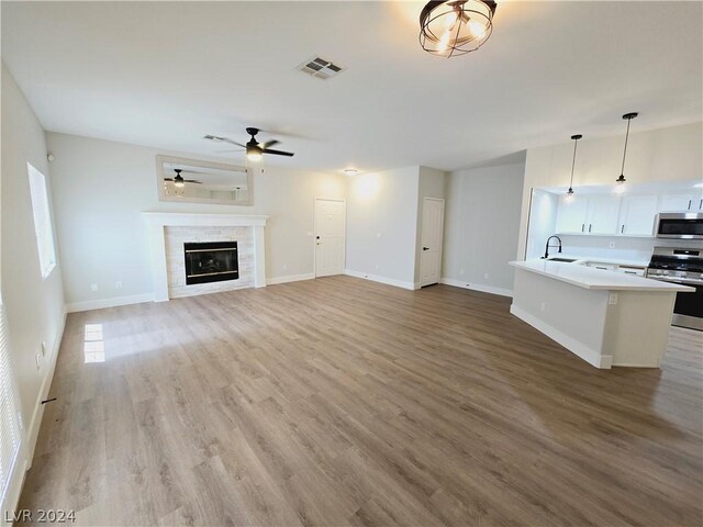 unfurnished living room with a healthy amount of sunlight, sink, ceiling fan, and light wood-type flooring