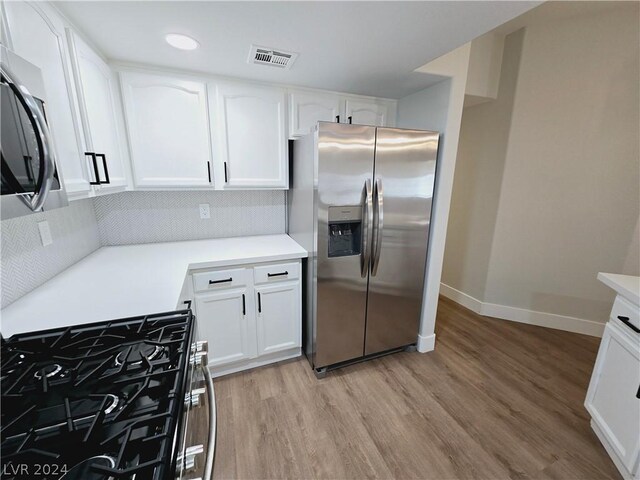 kitchen featuring stainless steel appliances, backsplash, white cabinets, and light hardwood / wood-style floors