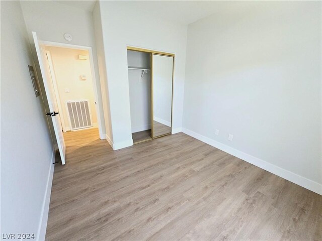 unfurnished bedroom with a closet and light wood-type flooring