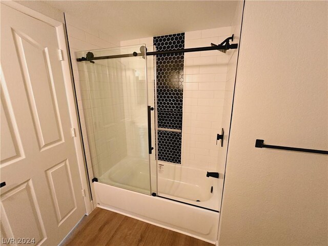 bathroom with combined bath / shower with glass door and hardwood / wood-style floors