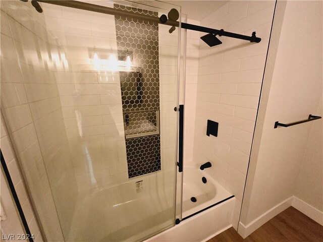 bathroom with wood-type flooring and combined bath / shower with glass door