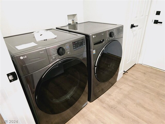 laundry room featuring independent washer and dryer and light hardwood / wood-style floors