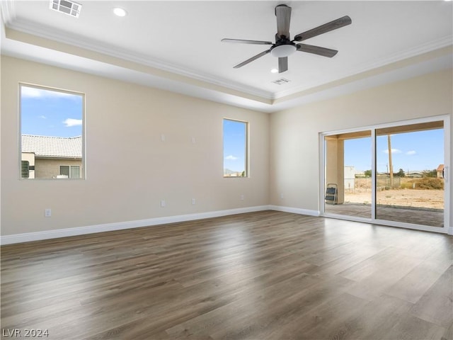 unfurnished room with ceiling fan, a wealth of natural light, a tray ceiling, and ornamental molding