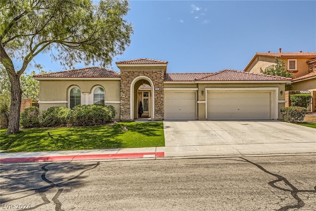 mediterranean / spanish-style home with a garage and a front lawn