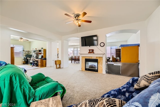 carpeted living room featuring a fireplace and ceiling fan