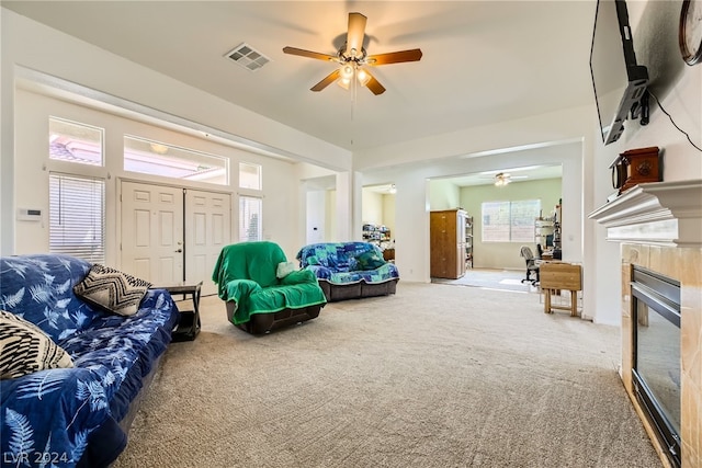 living room featuring light colored carpet, a tile fireplace, and ceiling fan