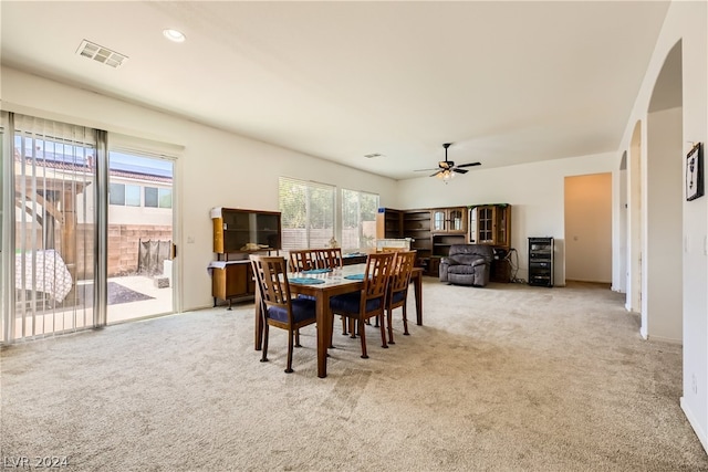 dining space with ceiling fan and light colored carpet