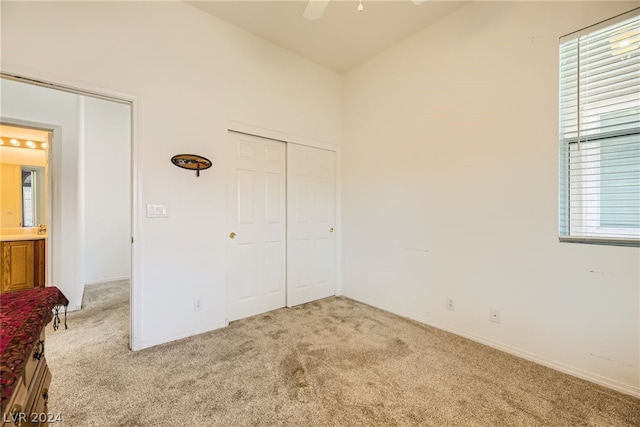 unfurnished bedroom featuring light carpet, a closet, and ceiling fan