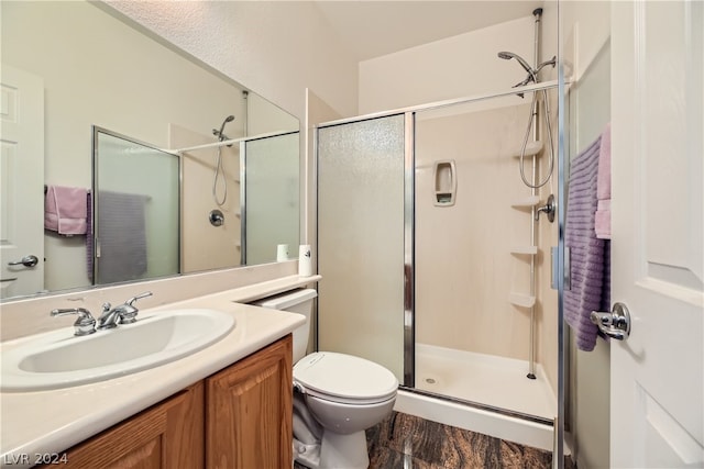 bathroom featuring hardwood / wood-style flooring, a shower with shower door, toilet, and vanity