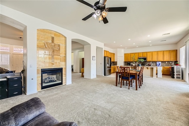 carpeted dining room with a tile fireplace and ceiling fan