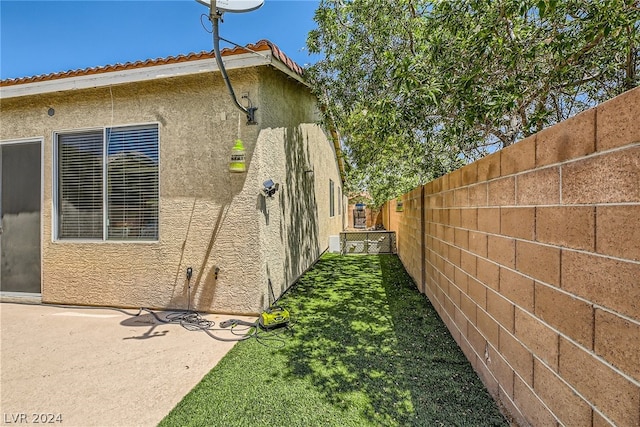 view of side of home with a patio and a lawn