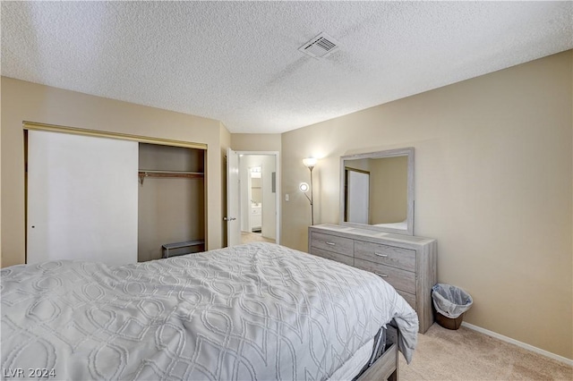 bedroom with light colored carpet, a textured ceiling, and a closet