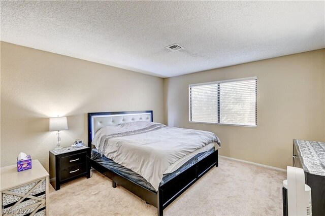 bedroom with light carpet and a textured ceiling