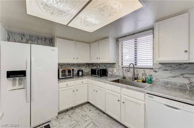 kitchen with tasteful backsplash, sink, white cabinets, and white appliances