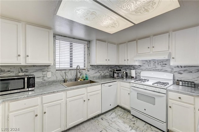 kitchen with sink, white appliances, white cabinets, and backsplash