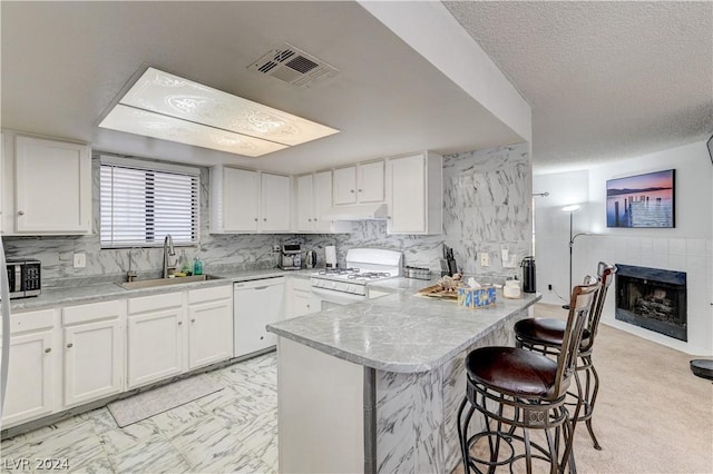 kitchen with white appliances, a kitchen breakfast bar, sink, and white cabinets