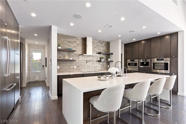 kitchen with decorative backsplash, dark wood-type flooring, black electric cooktop, and a kitchen island with sink