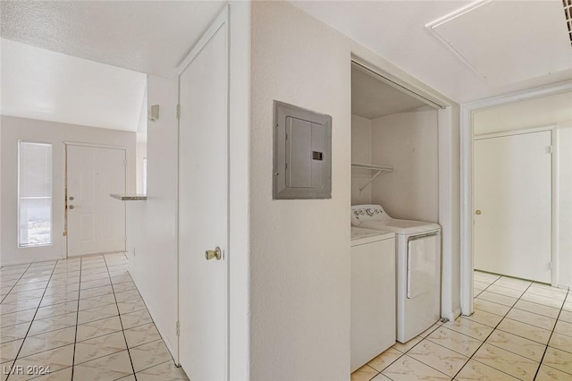 clothes washing area with electric panel, washing machine and dryer, and light tile patterned flooring