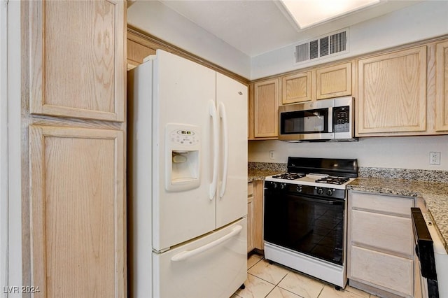 kitchen featuring black gas range oven, light brown cabinetry, white fridge with ice dispenser, light tile patterned floors, and light stone countertops