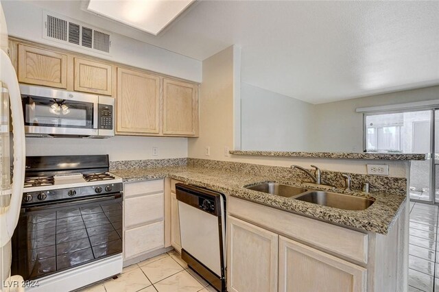 kitchen featuring sink, dishwashing machine, light stone counters, kitchen peninsula, and gas stove