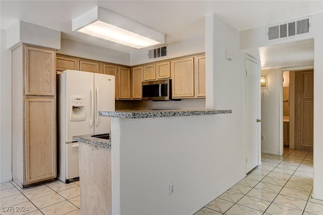 kitchen with white refrigerator with ice dispenser and light brown cabinetry