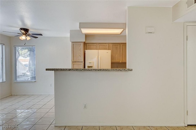 kitchen with ceiling fan, white refrigerator with ice dispenser, kitchen peninsula, and light tile patterned floors