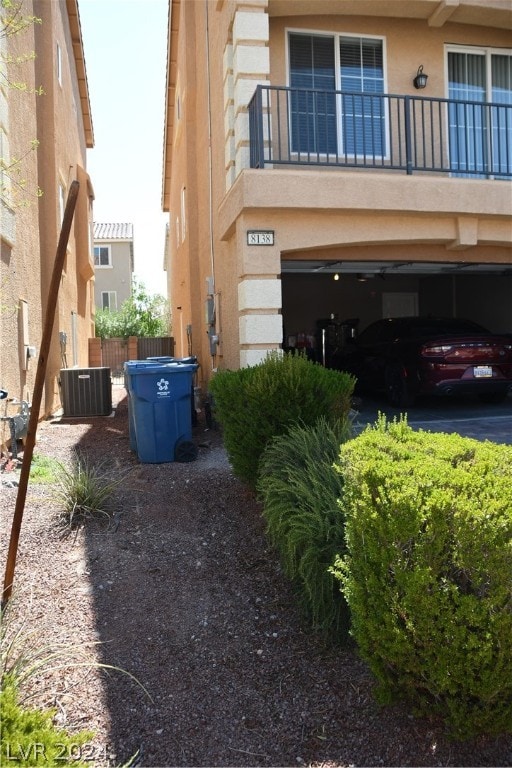 view of property exterior with a garage, a balcony, and cooling unit