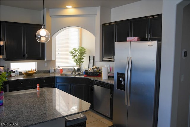 kitchen featuring light tile patterned flooring, sink, appliances with stainless steel finishes, pendant lighting, and dark stone counters