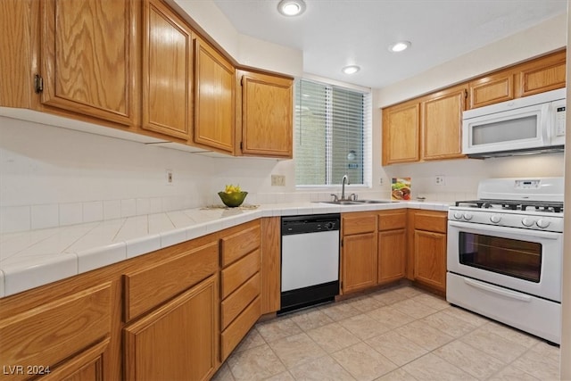 kitchen featuring light tile patterned floors, white appliances, tile counters, and sink