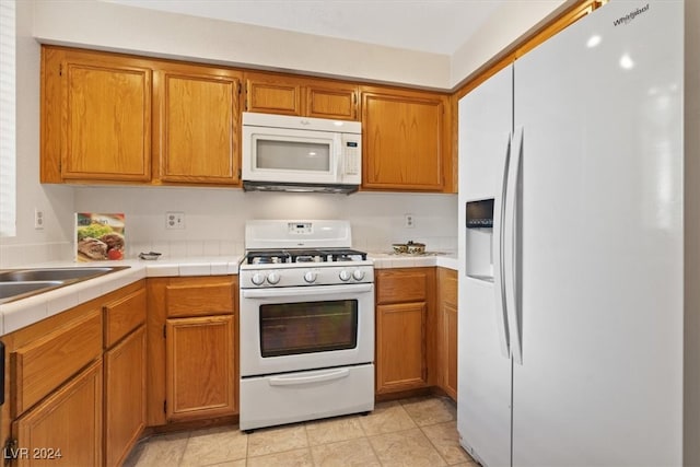 kitchen with tile countertops, light tile patterned floors, and white appliances