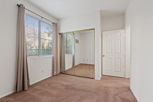 unfurnished bedroom with light colored carpet and a closet