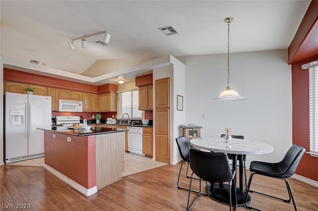 kitchen with light tile patterned flooring, rail lighting, white appliances, a center island, and vaulted ceiling