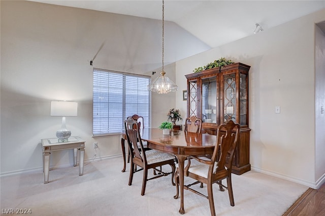 dining area featuring vaulted ceiling, hardwood / wood-style floors, and an inviting chandelier