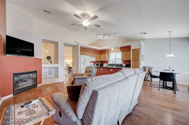 living room featuring sink, rail lighting, ceiling fan, and light hardwood / wood-style floors