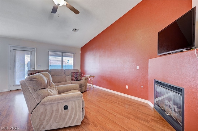 living room with light hardwood / wood-style flooring, lofted ceiling, and ceiling fan