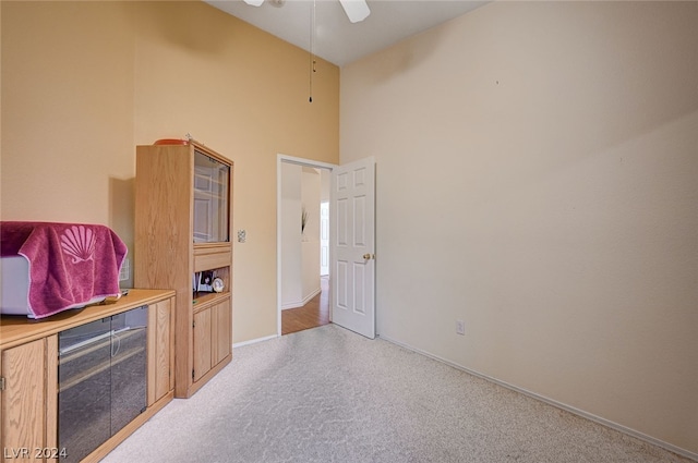 interior space with light hardwood / wood-style floors, ceiling fan, and a towering ceiling