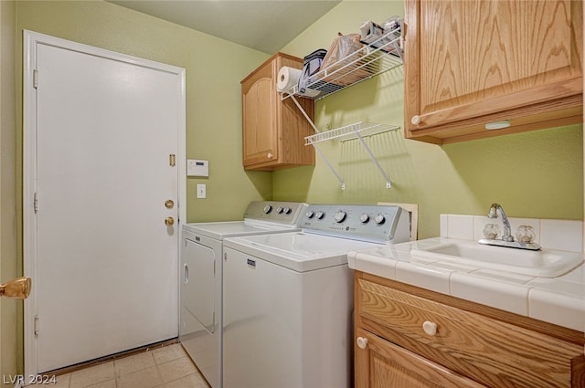 clothes washing area featuring light tile patterned flooring, separate washer and dryer, cabinets, and sink