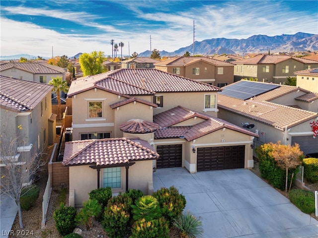 mediterranean / spanish-style home featuring a mountain view, solar panels, and a garage