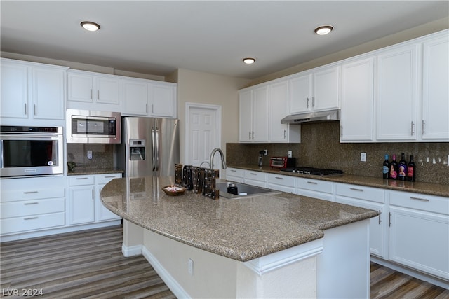 kitchen featuring a kitchen island with sink, tasteful backsplash, dark hardwood / wood-style floors, and stainless steel appliances