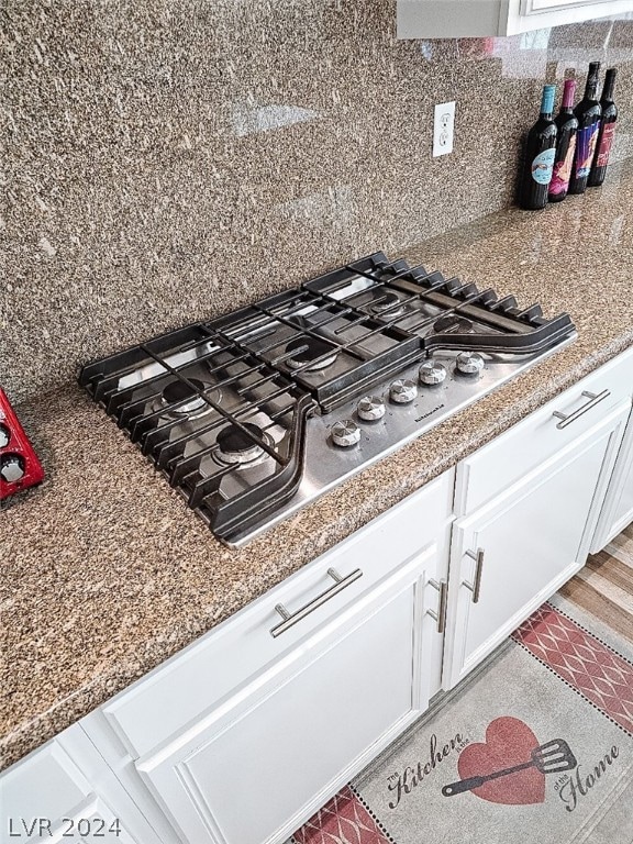 room details featuring white cabinetry, stainless steel gas stovetop, and tasteful backsplash