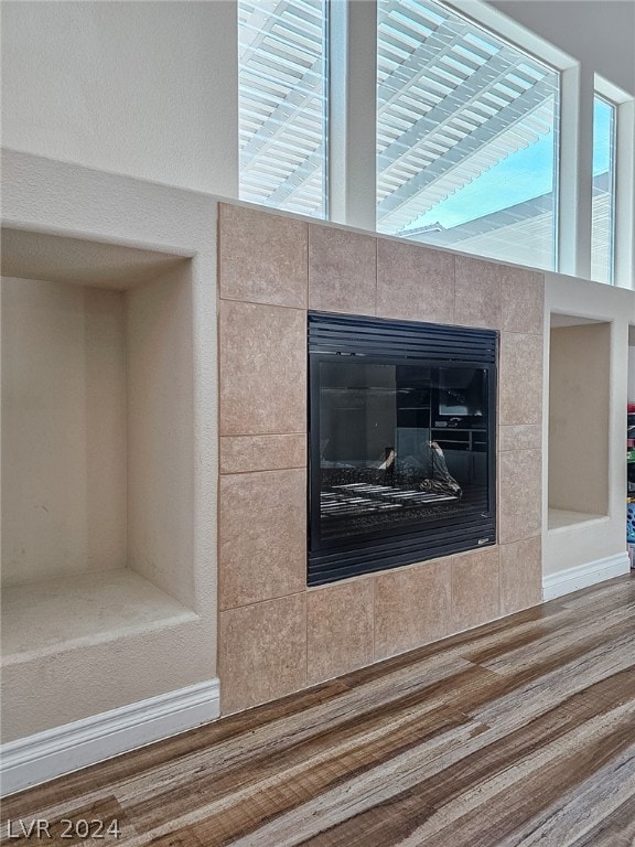 interior details featuring a tiled fireplace and hardwood / wood-style floors