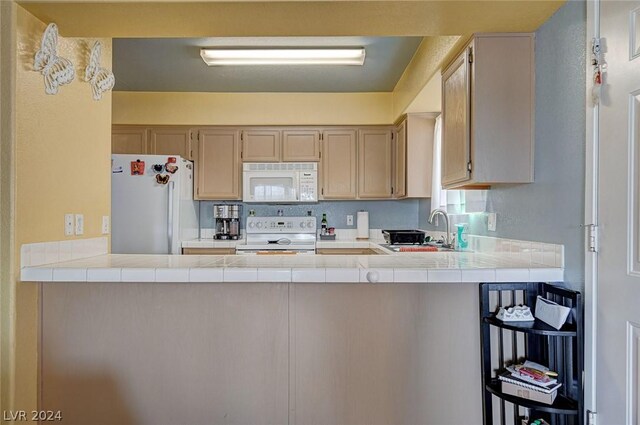 kitchen with white appliances, kitchen peninsula, tile countertops, light brown cabinetry, and sink