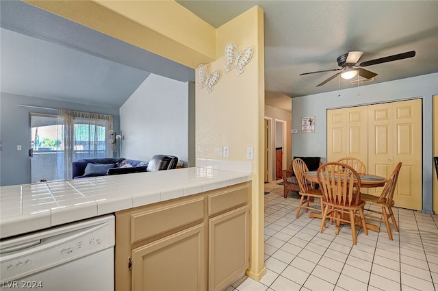 kitchen with ceiling fan, light tile patterned floors, dishwasher, and tile counters