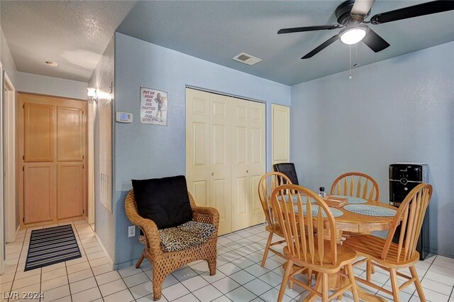 tiled dining area with a textured ceiling and ceiling fan