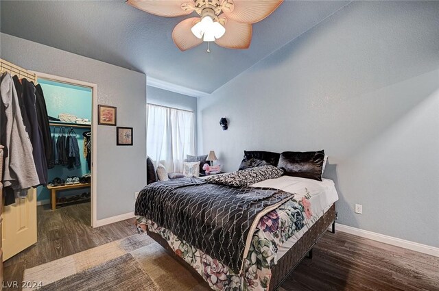 bedroom featuring a spacious closet, dark hardwood / wood-style flooring, a closet, lofted ceiling, and ceiling fan