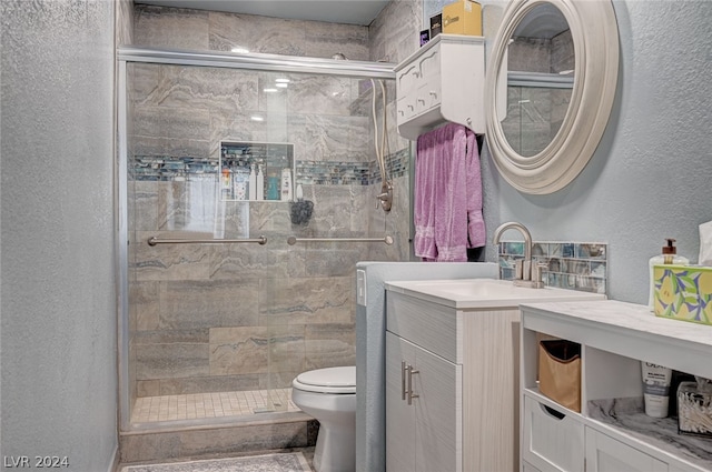 bathroom featuring a shower with door, toilet, and vanity